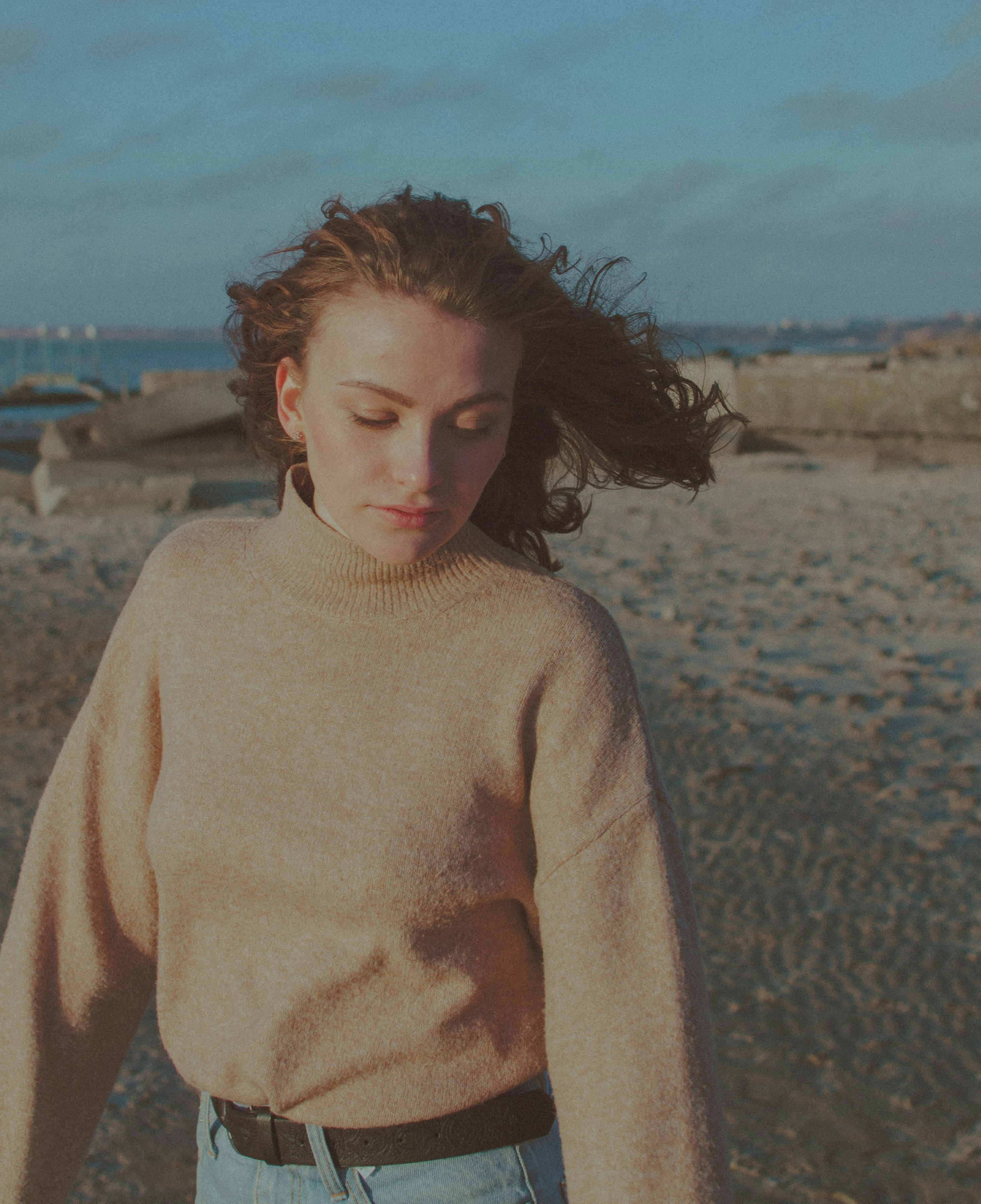 woman in white turtleneck sweater standing on beach during daytime